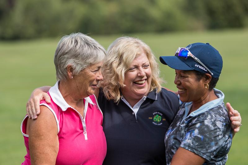 Friends playing golf together smiling.